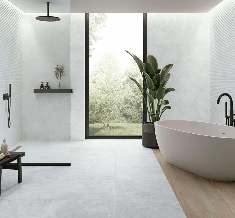 Baño luminoso con bañera, ducha y revestimientos Aparici.
